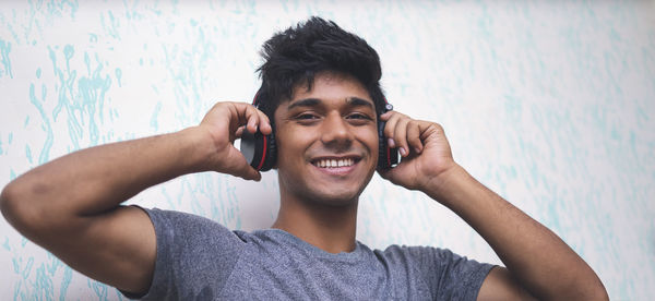 Portrait of young man using mobile phone against wall