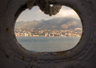 Cityscape by sea against sky seen through window