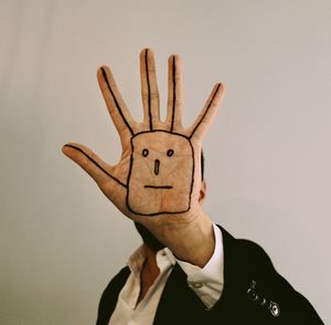 Portrait of man with arms raised against wall