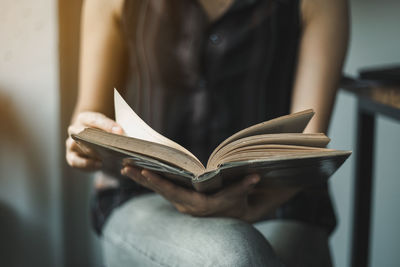 Midsection of woman reading book