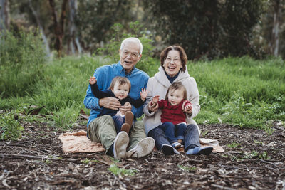 Portrait of senior active couple holding twin granddaughters outside