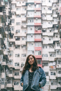 Portrait of smiling woman standing against buildings in city