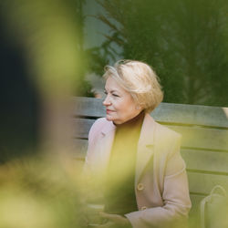 Young woman looking away while sitting outdoors