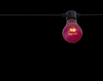 Close-up of illuminated light bulb against black background