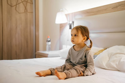 Portrait of young woman sitting on bed at home