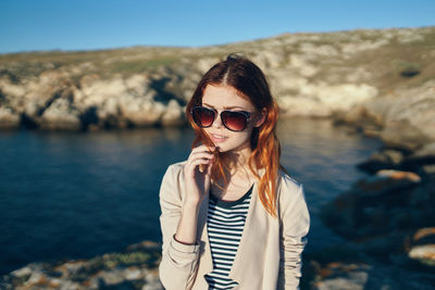 Portrait of young woman wearing sunglasses standing outdoors