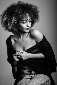 Afro woman sitting against wall