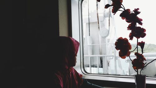 Midsection of woman with flowers in window