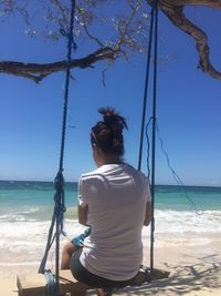 Rear view of woman sitting on beach