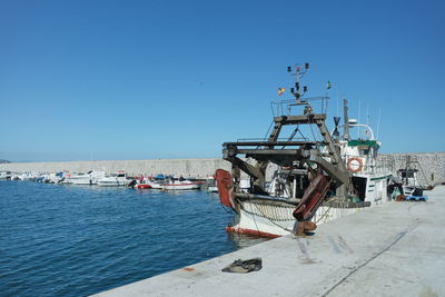 Ship moored at harbor against clear blue sky