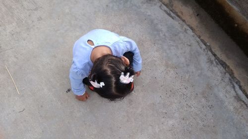 Directly above shot of girl crouching on footpath