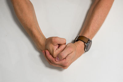 Close-up of hand holding ring over white background