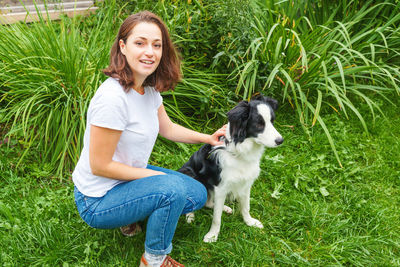 Portrait of young woman with dog on grass