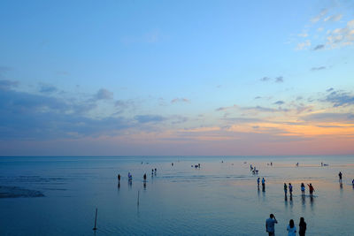 People on beach against sky during sunset