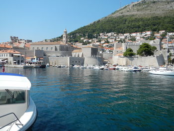 Sea by buildings in city against clear sky