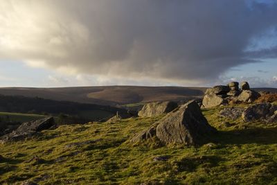 Rock formation on hill against sky