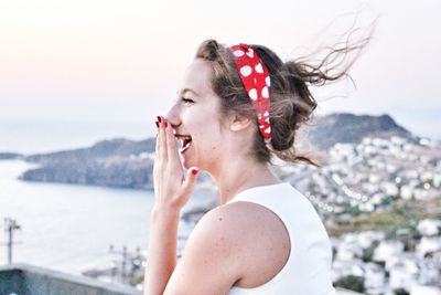 Close-up of woman laughing against sky