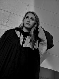 Portrait of young woman standing against wall