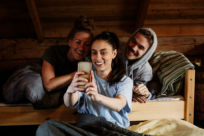 Smiling young woman taking selfie with enjoying with friends in cottage