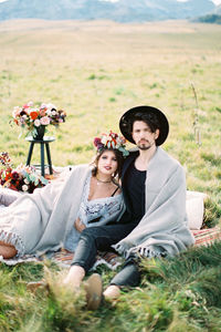 Portrait of smiling friends sitting on field