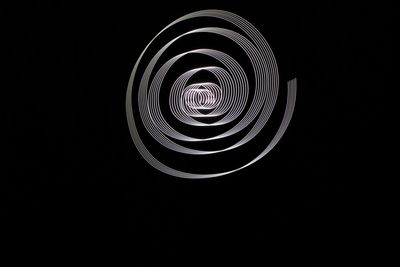 Close-up of spiral light over black background