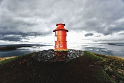 Lighthouse by sea against sky
