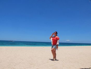 Full length of boy on beach against clear sky