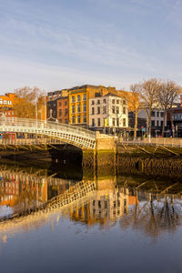Bridge over river in city against sky