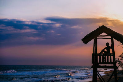 Silhouette people standing on beach against sky during sunset