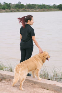 Full length of woman with dog standing by lake