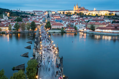 High angle view of illuminated buildings and bridge by river against sky