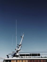 Low angle view of crane against clear blue sky