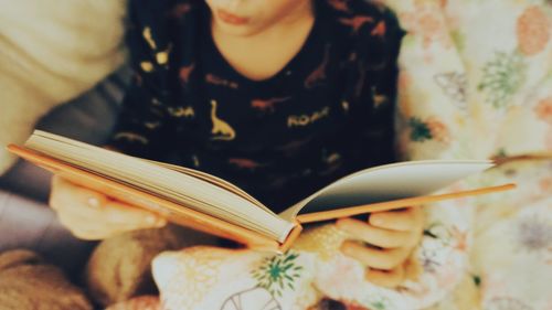 Midsection of boy reading book