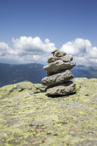 Stack of stones on rock against sky