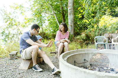 Side view of a family sitting next to a fire on a sunny day