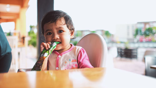 Portrait of cute boy sitting on table at cafe