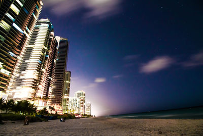 Buildings by beach in city at night