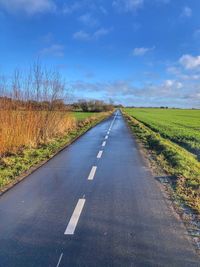 Road amidst field against sky