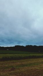 Scenic view of grassy field against cloudy sky