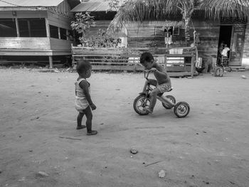 Baby boy looking at brother riding bicycle on land