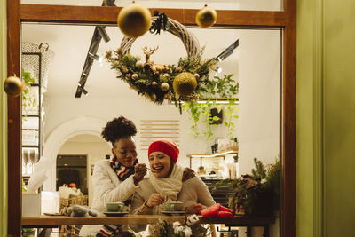 Women enjoying drinks in cafe seen through glass window