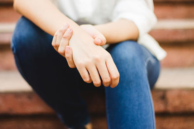 Midsection of woman holding her hand while sitting on steps