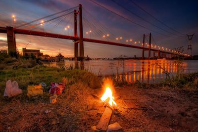 Campfire against illuminated zaratebrazo largo bridge at night