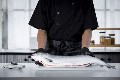 Rear view of man standing in kitchen