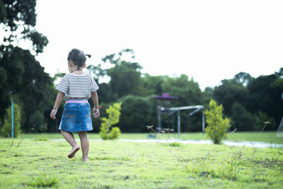 Rear view of woman walking on field