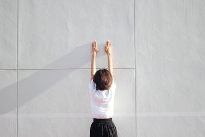 Rear view of woman standing against white wall