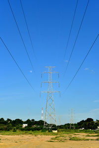 Low angle view of electricity pylon on field against clear sky