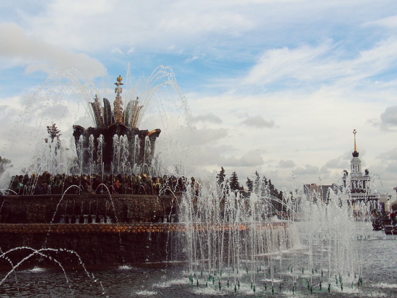 water, sky, building exterior, cloud - sky, built structure, architecture, fountain, cloudy, motion, spraying, weather, travel destinations, splashing, outdoors, city, famous place, day, travel, smoke - physical structure, cloud