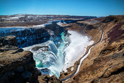 Aerial view of snowcapped mountains against clear blue sky - gulfoss, iceland.