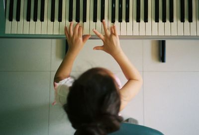 Directly above shot of girl playing piano at home